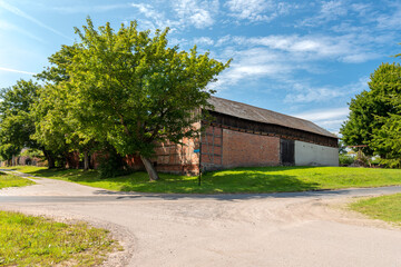 Beautiful countryside on a sunny day. A large old barn at the crossroads of rural streets. A small peaceful quiet village. Cisowo, Poland