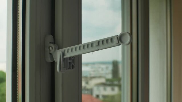 Master installed fixing limiter for opening plastic window and checks its operation. Close-up of hand in glove checking operation of window fittings. Home repairs. Installing window hardware