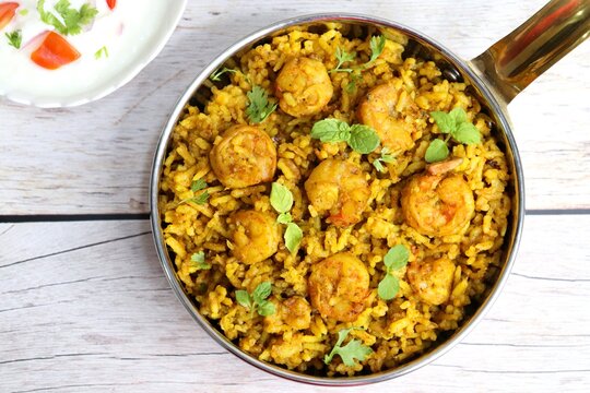 Prawns Biryani or shrimp Pulao. also called jheenga pilaf or jhinga biryani in India. known as Kolambi bhat in Marathi. Garnished with mint leaves, and coriander along with yogurt Raita. Copy space