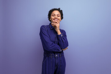 Fototapeta premium young successful woman with dark skin and black curly hair dressed in a blue denim suit