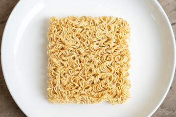 Instant noodles on white plate on brown wooden table
