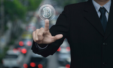 Businessman pressing bitcoin icon over blur of rush hour with cars and road in city, Choosing...