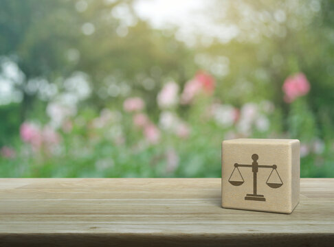 Law icon on wood block cube on wooden table over blur pink flower and tree in park, Business legal service concept