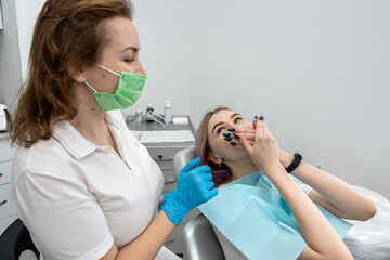 female patient sits at dentist and closes her mouth from female dentist because she is afraid.