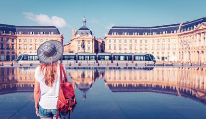 Rear view of woman visiting Bordeaux city in France - Place de la Bourse reflecting from the water...