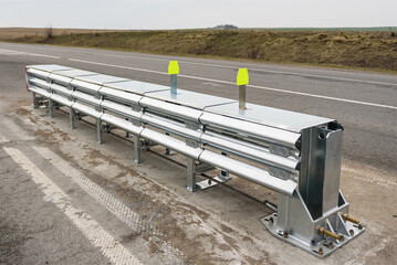 Installation of median crash barriers on highway. Metal road fencing of barrier type on freeway....