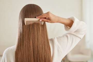 Fototapeta premium a young girl in a white coat takes care of her hair at home