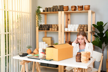 Fototapeta premium Caucasian young seller woman headache while thinking about handmade product quality and packaging design problem for customer online in office store