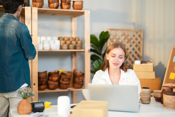 Caucasian entrepreneur female promote product promotion on e-commerce website while Asian freelance young boy team check retail store on shelf for improve small business