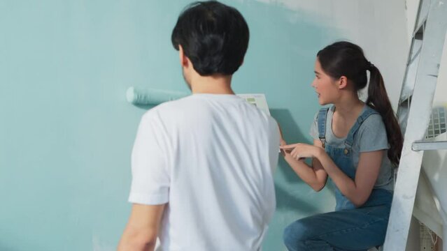 Young Asian marry Couple choosing paint color palette swatch together while renovation home new home relocation, happiness asian male and female enjoy painting wall colour with cheerful in a new room