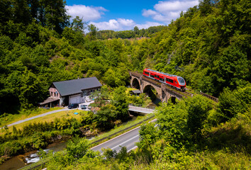 Train passing historic brick bridge over Hoenne river in Sauerland Germany on picturesque...