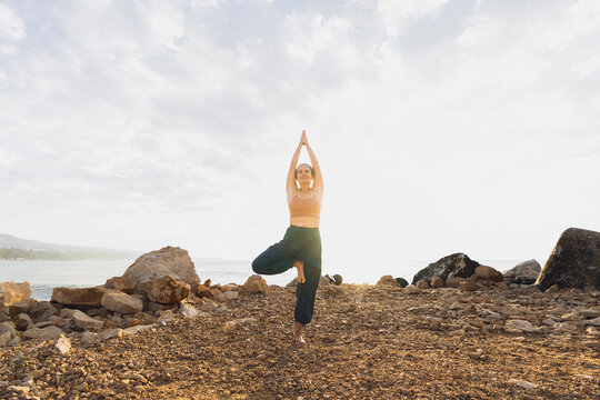 Woman practicing tree pose at beach