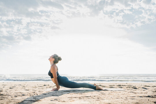 Woman practicing cobra pose at beach