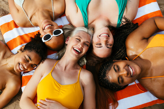 Multiracial friends lying down on beach towel
