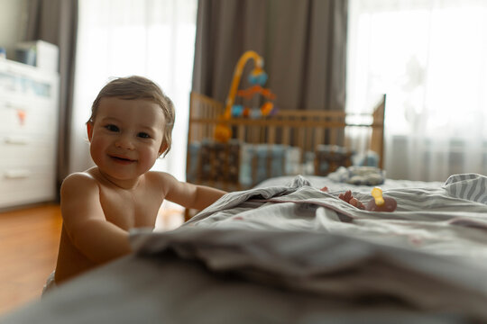 Smiling baby girl standing with support of bed at home