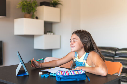 Smiling girl homeschooling with tablet PC at home