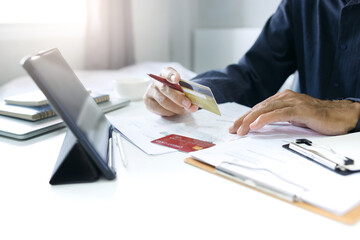 Asian businessman holding credit card and using tablet computer to start new business online, check...