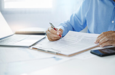 Asian businessman reviewing document reports at office workplace with computer laptop. legal...