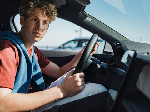 Young man driving car on sunny day