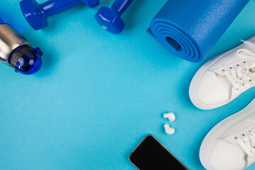 The concept of sports accessories. Photo of blue dumbbells and a blue exercise mat, white sneakers and other sports equipment.
