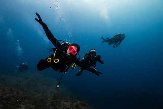 Young men and woman doing scuba diving undersea