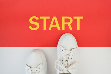 A pair of white sneakers in front of the start line with the word start printed on a red background. Step into the Future