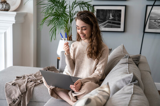 Happy young woman showing pregnancy testing kit on video call over laptop