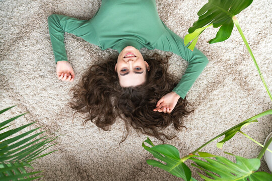 Smiling young woman lying on rug at home