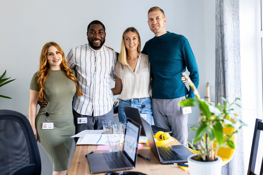 Smiling multiracial colleagues standing together in office