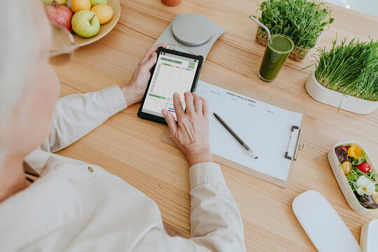 Woman using nutrition tracker app on tablet PC at home