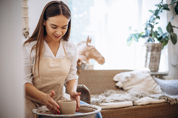 Woman working on pottery wheel creating a bowl