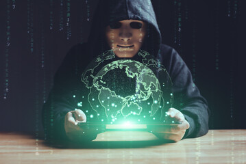 Black hat hacker using tablet on table sensitive data cyber crime hack in black dark room green...