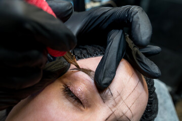 The cosmetologist makes a permanent makeup of the eyebrows - obrazy, fototapety, plakaty