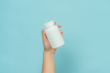 White plastic tube in female hand. Bottle for pill, capsule or supplement. Product branding mockup