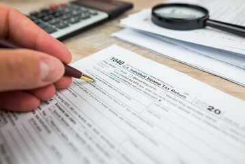 Close-up of a woman's hand filling out an empty tax form in the office.