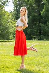 Fototapeta na wymiar Portrait of a young beautiful blonde woman in a long red skirt