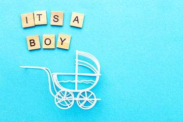 Its a boy. Little vintage white baby carriage stroller or pram on a blue background.
