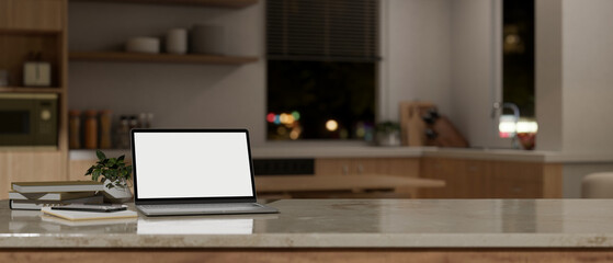 Obraz na płótnie Canvas A portable laptop computer mockup on a tabletop in a modern kitchen at night.