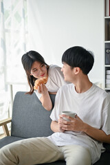 Obraz na płótnie Canvas A cute Asian girlfriend playing and feeding a yummy croissant to her boyfriend