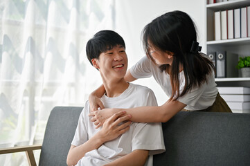 A cute young Asian girl embracing or hugging her boyfriend from behind