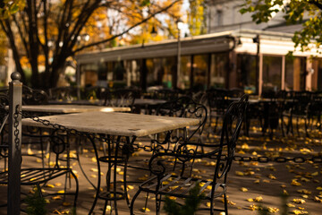 table and chairs of a street cafe in autumn leaves.