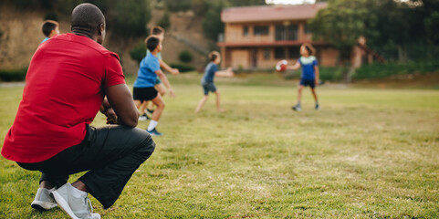 Fototapeta premium Coach having a practice session with kids in a school