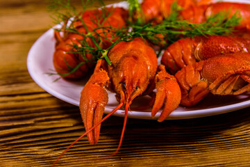 Plate with boiled crayfishes on wooden table