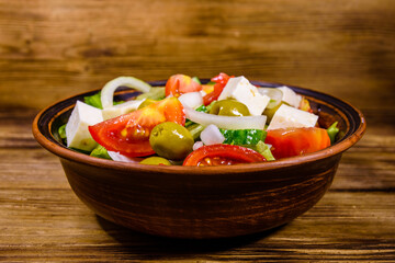 Ceramic plate with greek salad on wooden table
