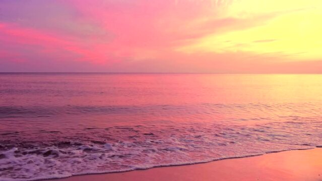 Beautiful sea coast with reflection of pink sunrise light on the colors  purple and yellow sky background. Calm shore waves scene, by the beach with clouds, slow motion, hd. ProRes 422 HQ.