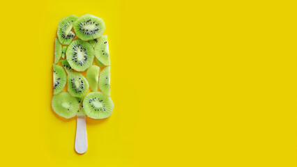 Kiwi slices laid out in the form of ice cream, top view. Ice cream on a stick, banner with yellow...