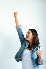Euphoric woman looking at her smartphone and raising her arm.