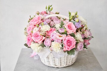 Flower arrangement in Wicker basket. Beautiful bouquet of mixed flowers on a marble table. Floral shop concept . Handsome fresh bouquet. Flowers delivery