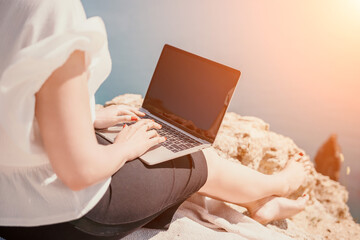Fototapeta premium Woman sea laptop. Business woman in yellow hat working on laptop by sea. Close up on hands of pretty lady typing on computer outdoors summer day. Freelance, digital nomad, travel and holidays concept.