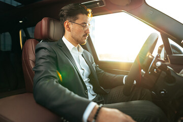 Young businessman in elegant suit driving luxury car